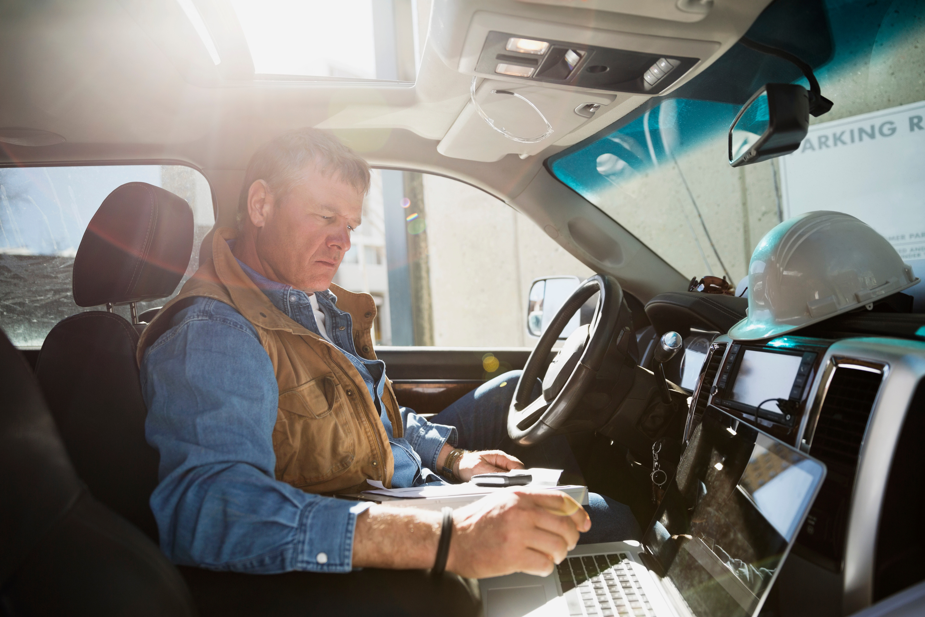 Builder sitting in a truck using a laptop