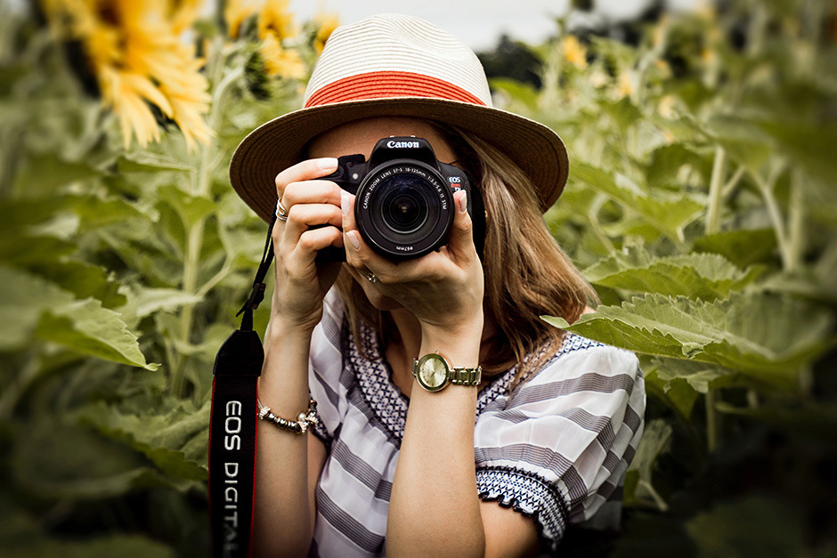 A woman taking a photo using a used Canon EOS Rebel DSLR.