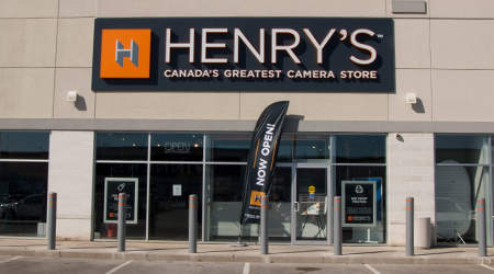 View of a Henry's store front with a "Now Open" flag placed by the door