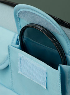 A lens filter is partially tucked into a small pocket on a camera bag