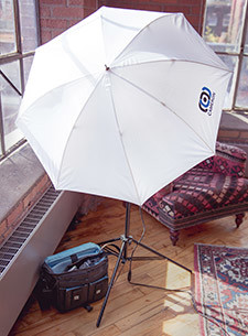 White lighting umbrella open in a room with large windows