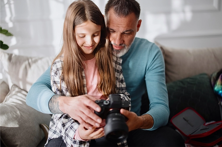 Father and daughter looking at images on a camera LCD.