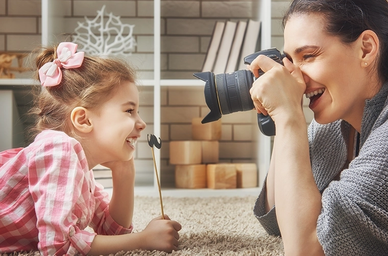 Mother taking a photo of her daughter using a DSLR camera