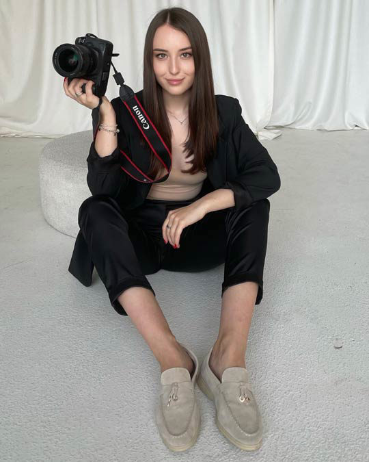 A young white woman with long hair holding a camera