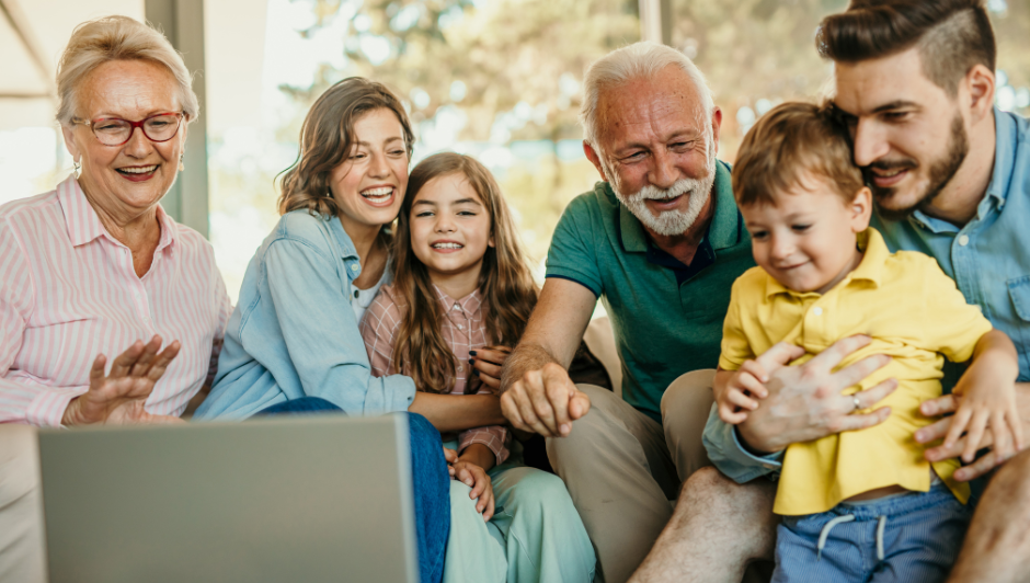 A large family sitting around a laptop 