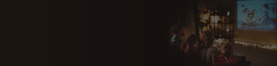 A family sitting on a couch watching home videos