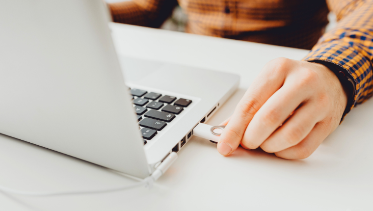 A close up of a man plugging a U.S.B. key into a laptop