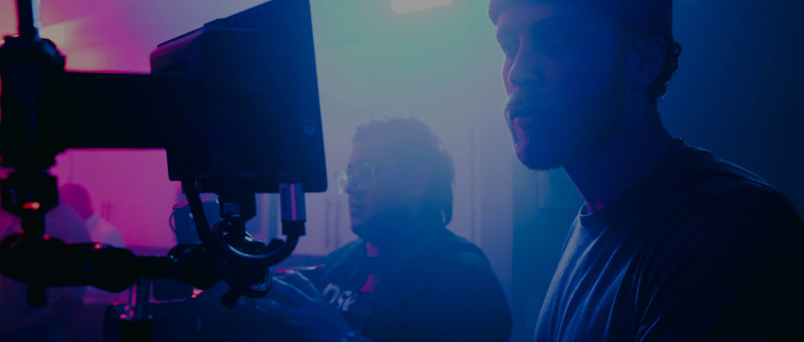 Two young men operating video equipment in a darkly lit studio