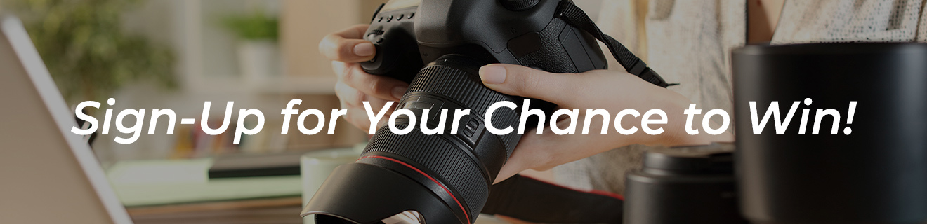A woman's hands holding a camera. Text reads, sign up for your chance to win.