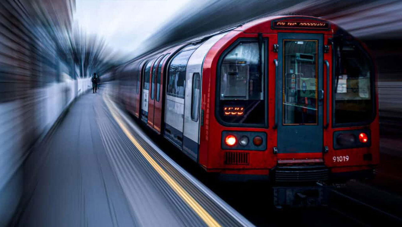 A subway car stopped on the track while another subway passes by all blurred.