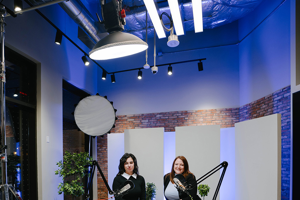 Various studio lights above two women recording a video podcast