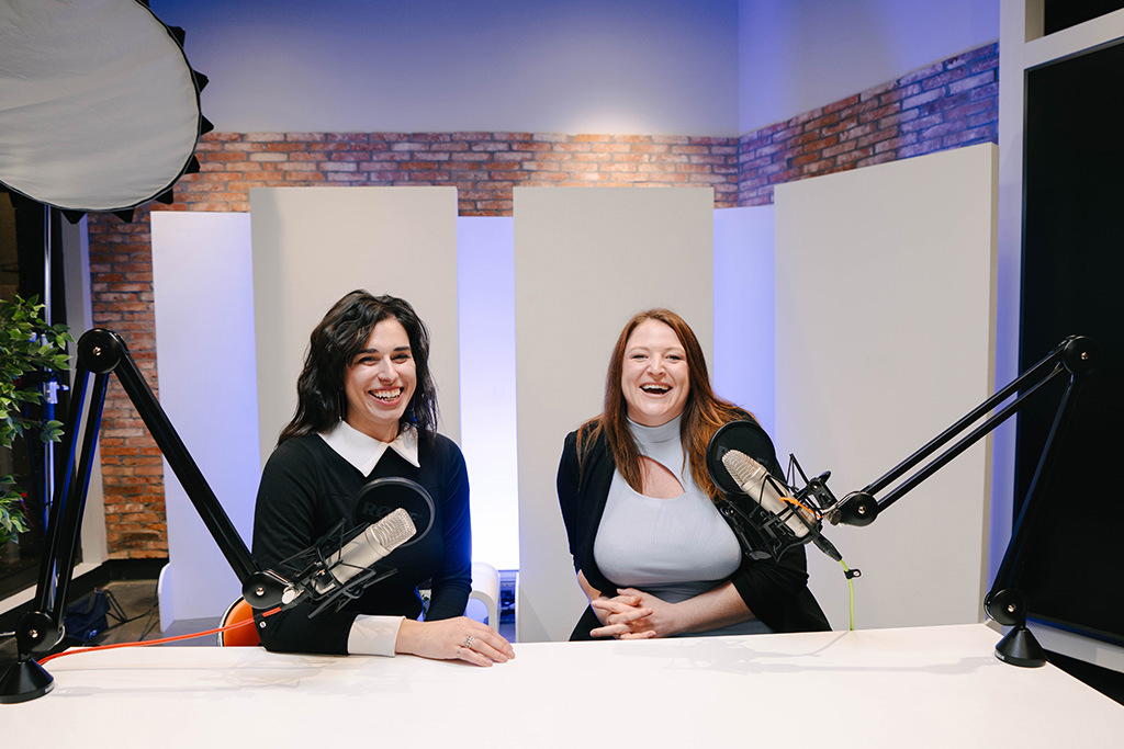 Two women sitting at a table recording a video podcast