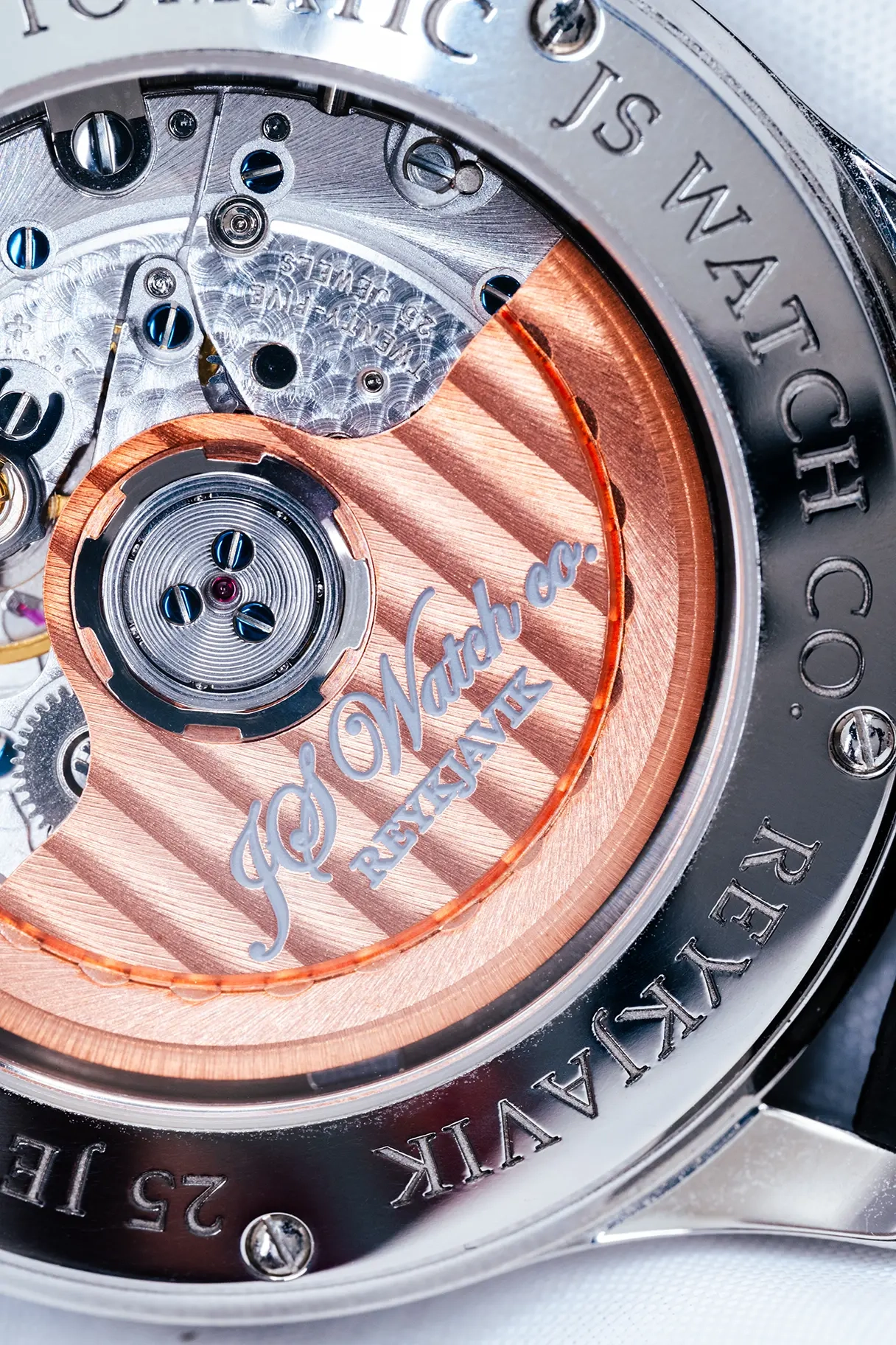 Macro photo of the face of a J&S Co. watch showing details of brushed copper, ground metal, tiny screws and gears