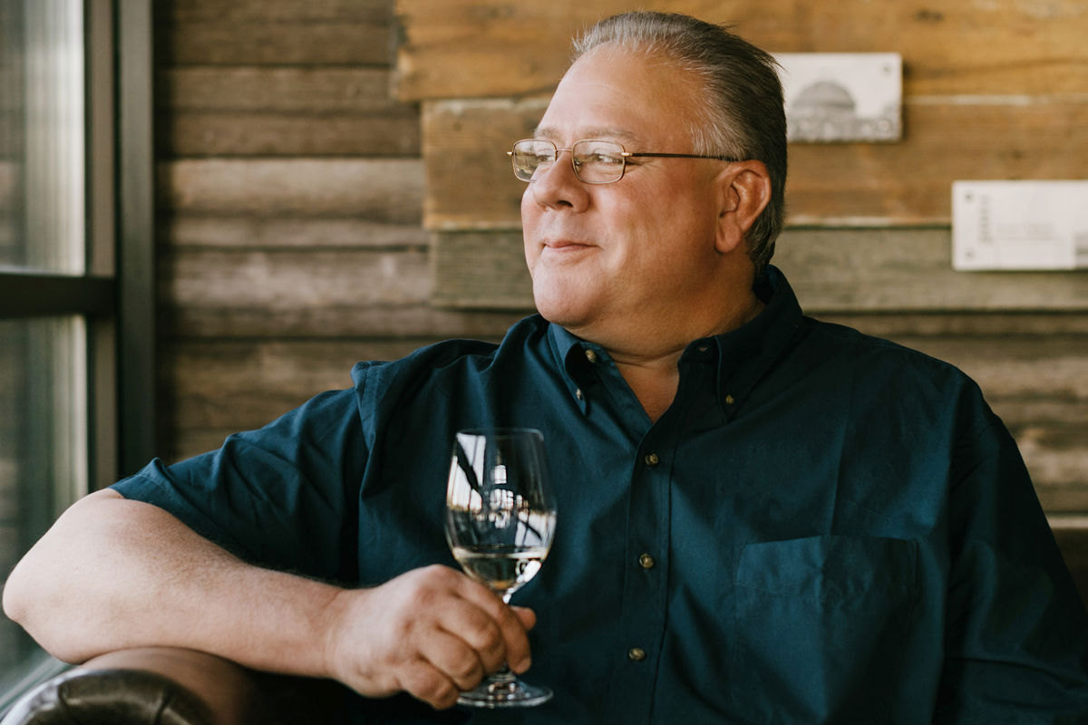 Winemaker Keith Kenison sitting down with a glass of wine