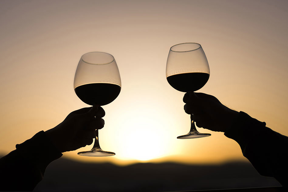 Wine glasses being held up against the sunset