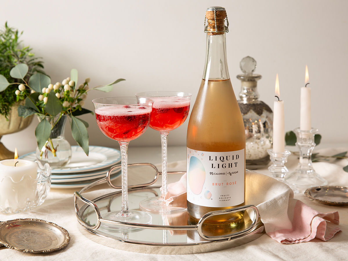 Bottle of Liquid Light Brut Rosé on a table with glasses
