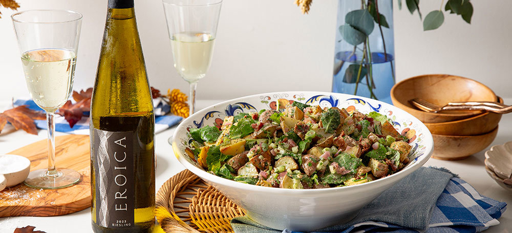 Bowl of german potato salad with a bottle of Eroica Riesling