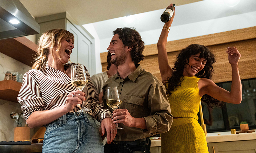People in the kitchen, drinking wine and dancing