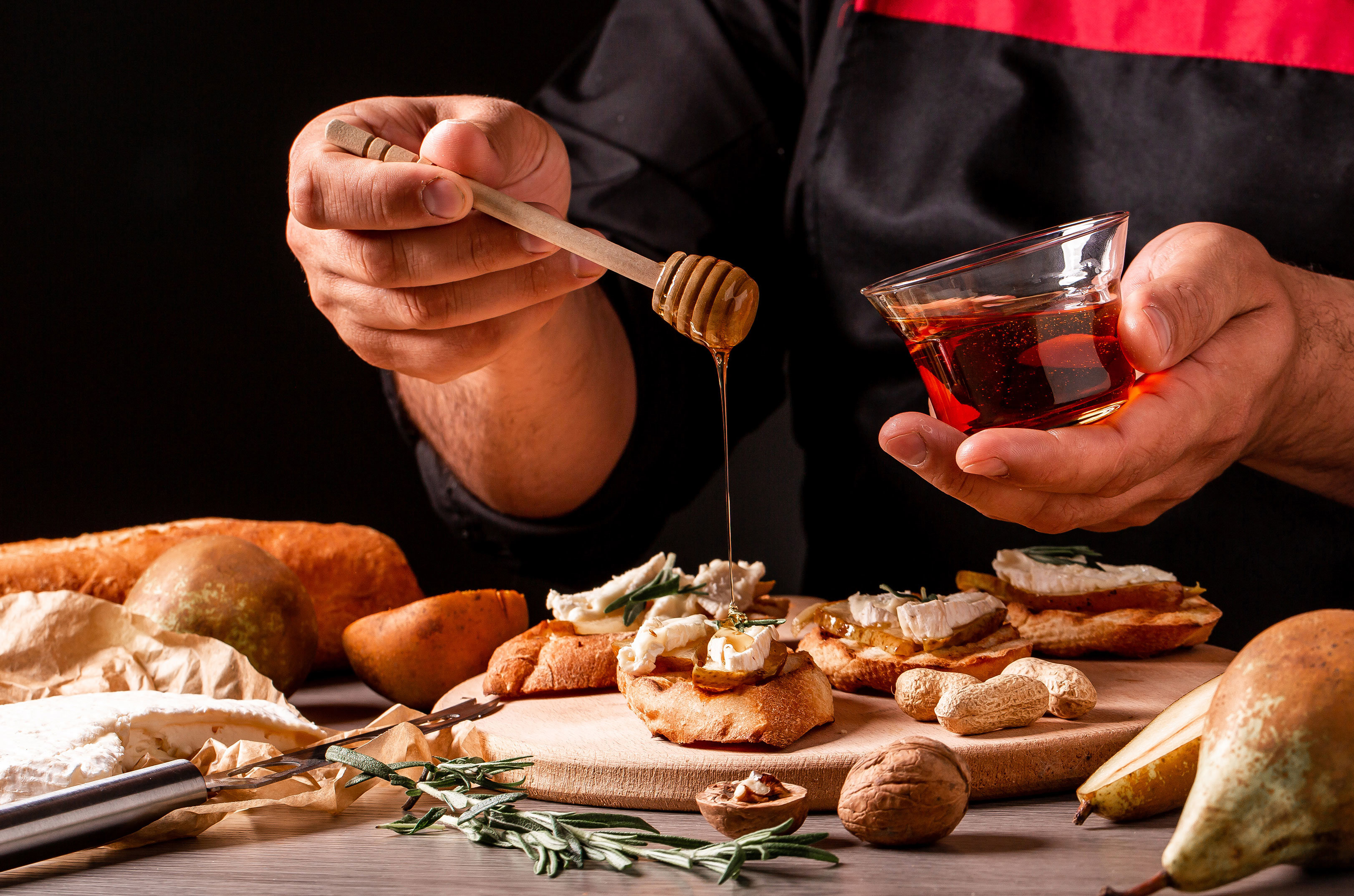person drizzling honey over goat cheese on a baguette