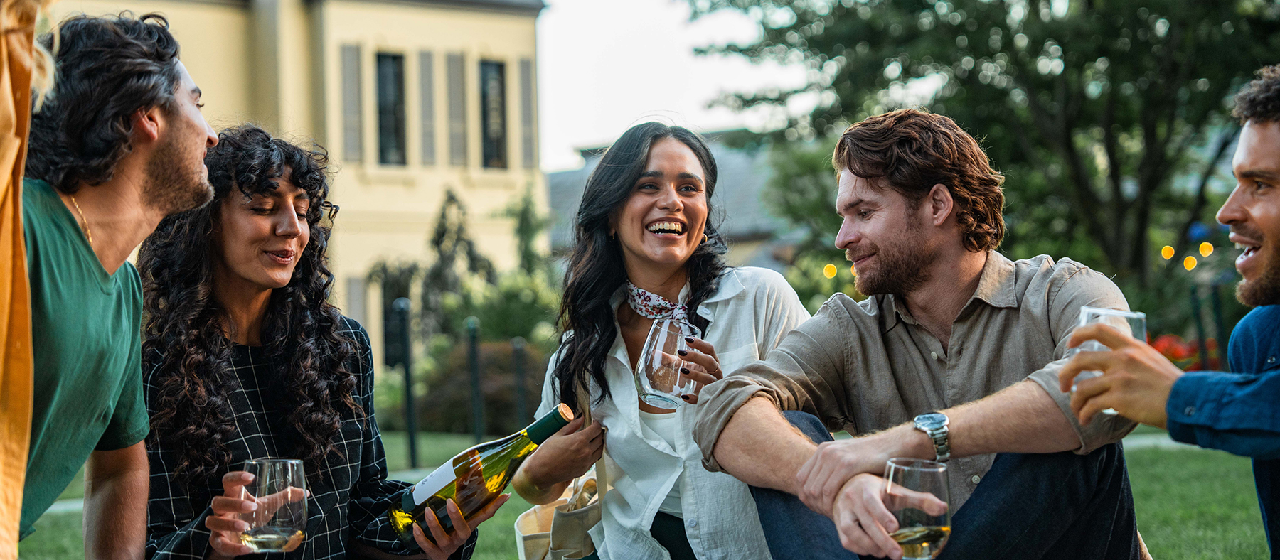 people sitting on the lawn in front of the Chateau drinking wine