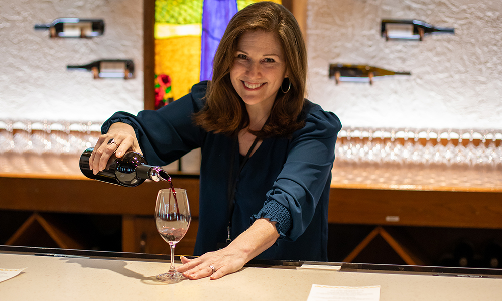  a tasting room attendant pouring red wine at the wine bar