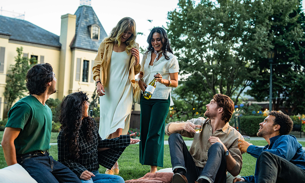 People enjoying wine on the grass in front of the winery