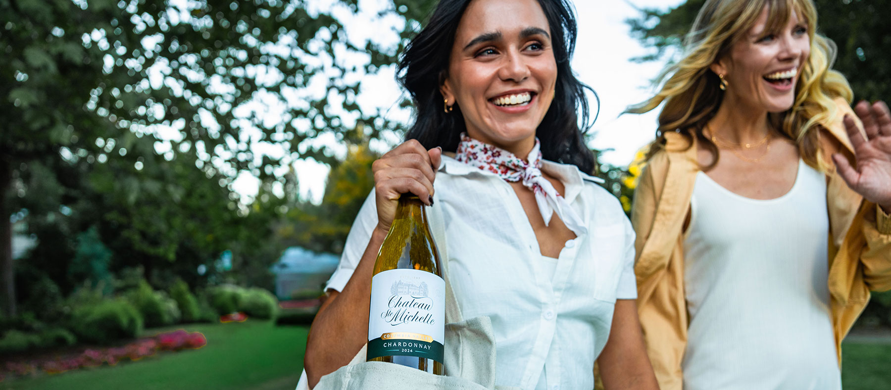 Two women walking with a bottle of Chardonnay