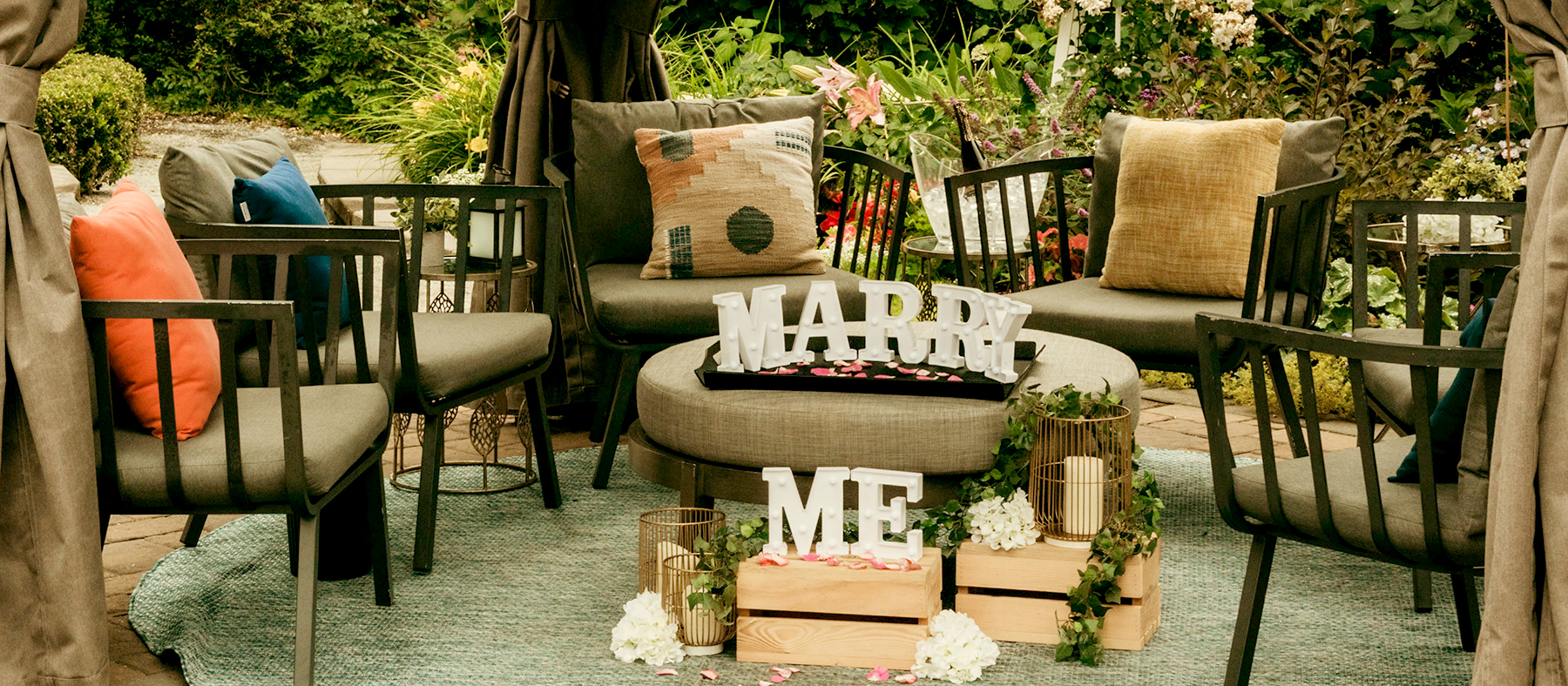 Chairs surrounding a table with the words "marry me" under a cabana