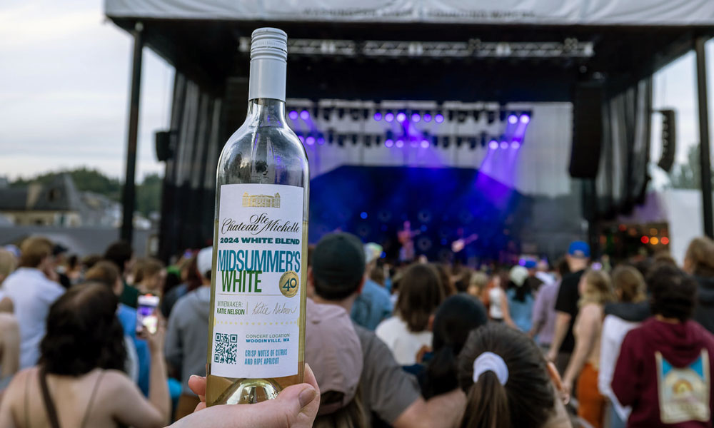 Someone holding a bottle of Midsummer's White at a concert