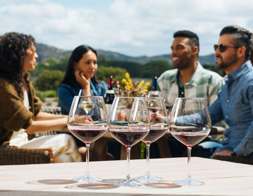 4 wine glasses with people socializing in the background