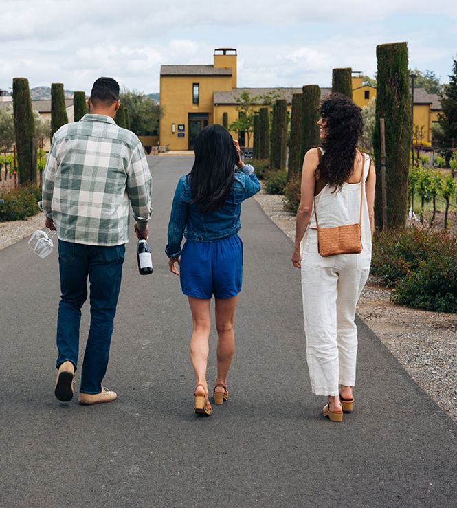 People walking toward Patz & Hall winery with wine bottles and glasses