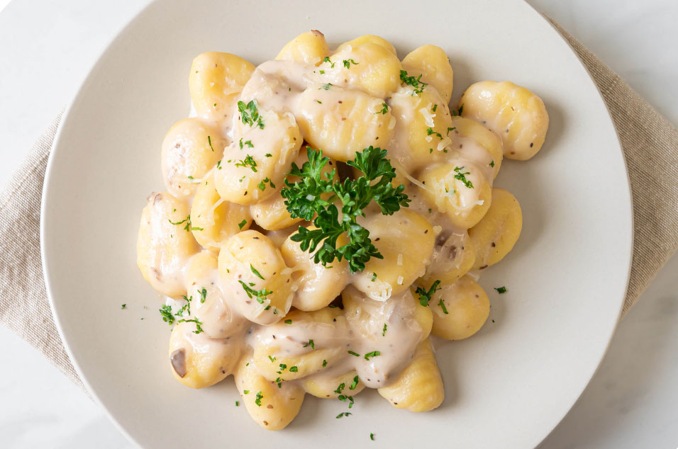 A plate of creamy gnocchi coated in a rich corn Mornay sauce