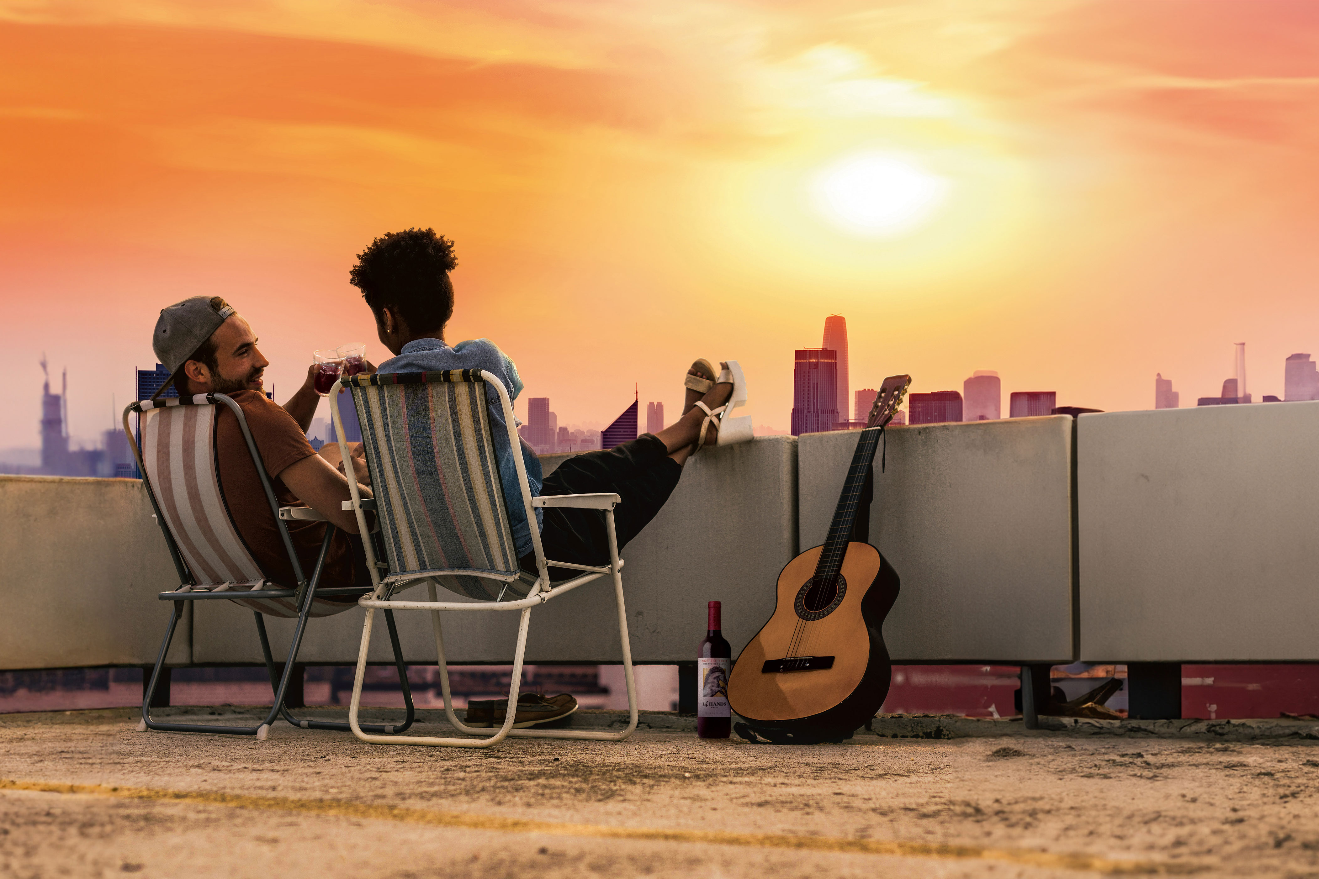 People sitting on a rooftop clinking glasses of red wine