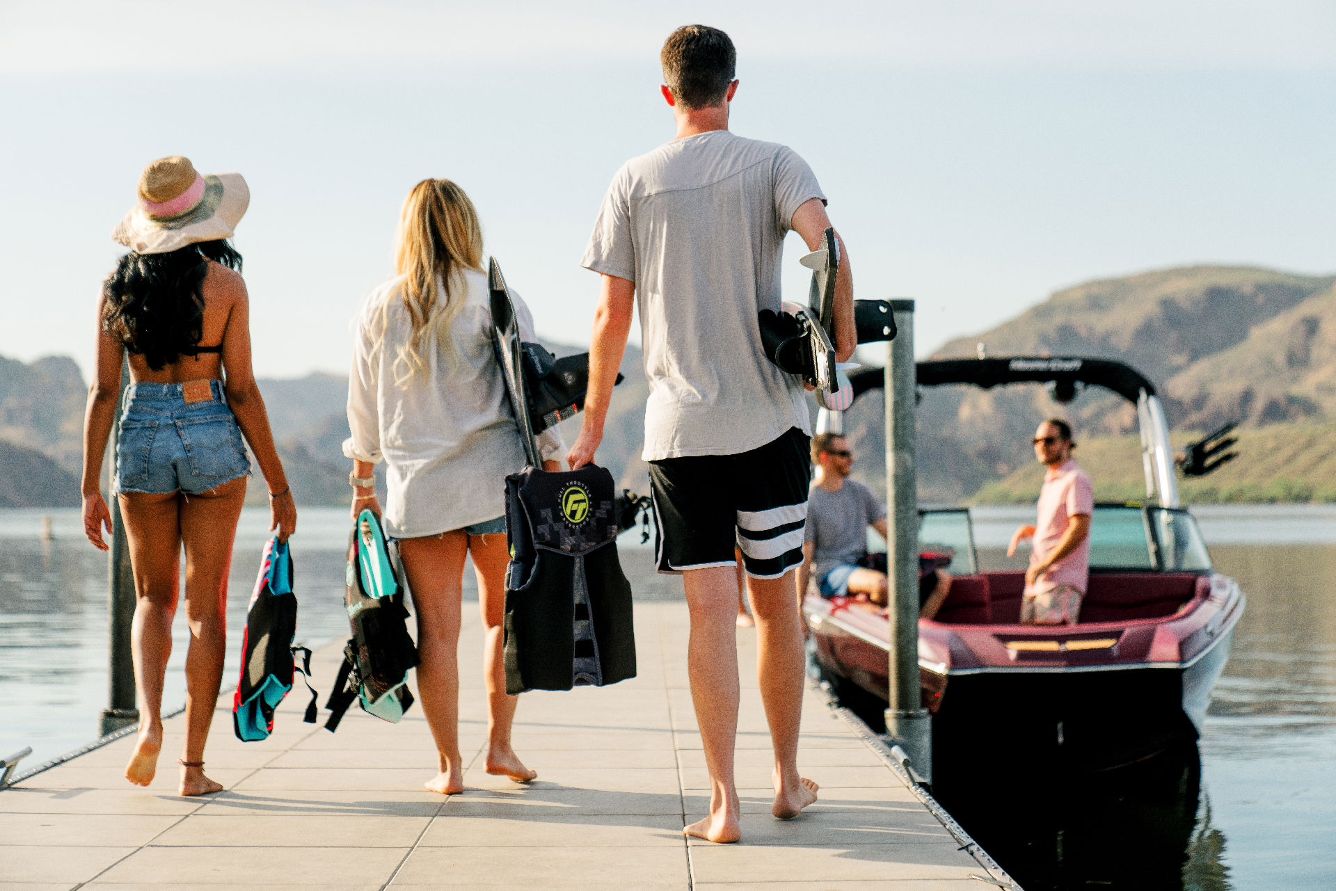 Three people walk on a dock towards a boat.