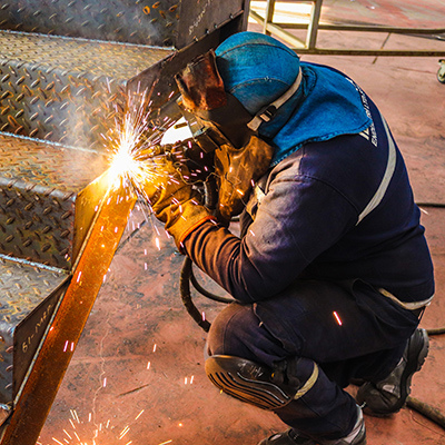 A man performing welding on metal stairs, showcasing craftsmanship and attention to detail in a professional setting