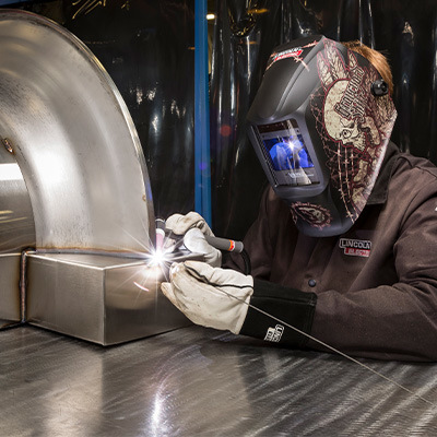 Welder TIG welding steel in shop