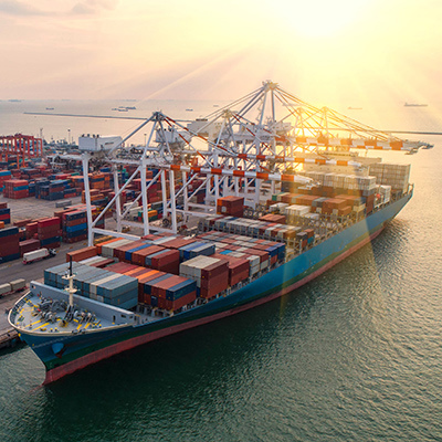 Un énorme porte-conteneurs est à quai, entouré de grues et d'installations portuaires, se préparant à recevoir des marchandises