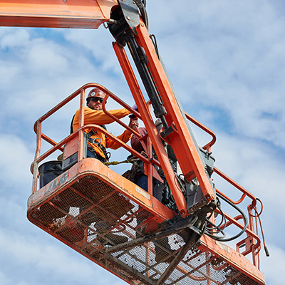 Un ouvrier de la construction à bord d'un élévateur à nacelle travaille sur un chantier de construction, soulignant l'importance de la sécurité et des compétences