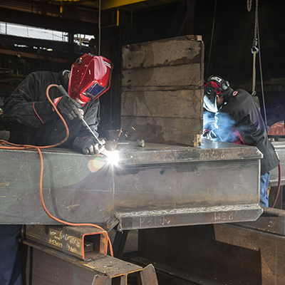 Deux hommes soudant ensemble dans un environnement industriel, démontrant la précision et le travail d'équipe dans les opérations industrielles