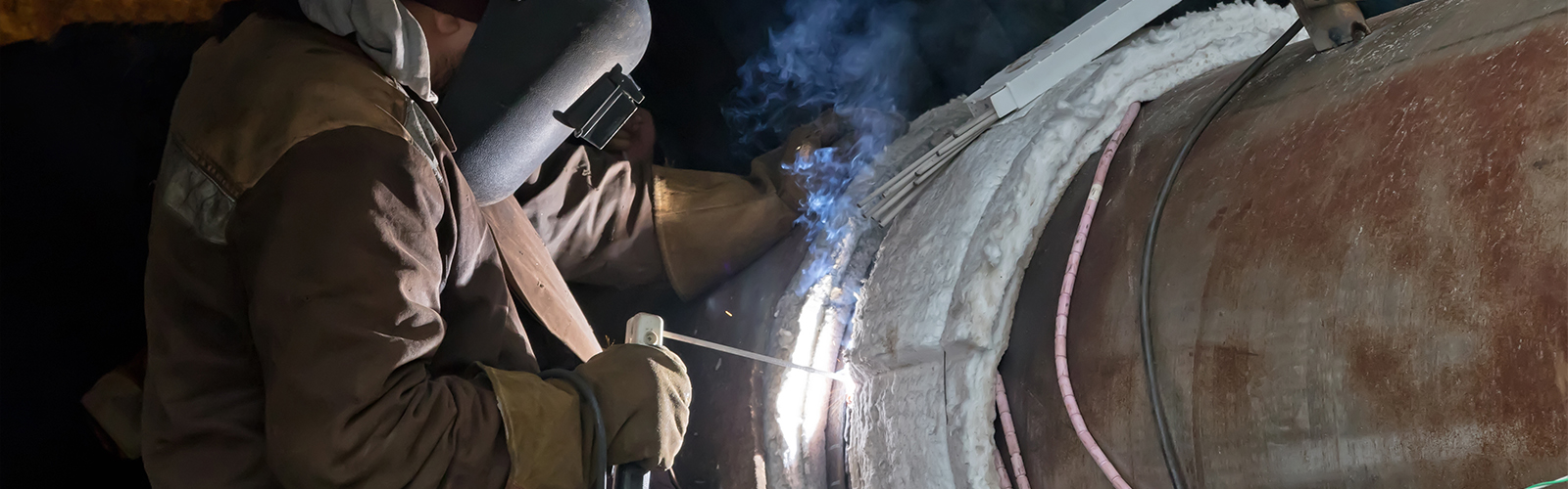 A welder performs stick welding on a pipe, utilizing induction heating technology for improved results