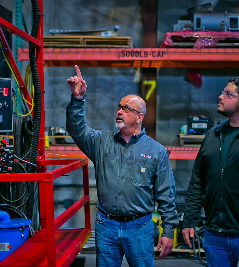 Employee showing customer welding equipment in warehouse