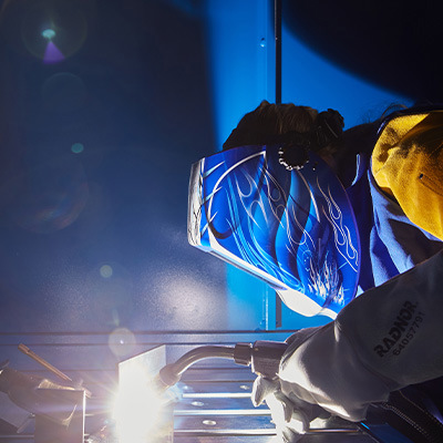 Welder performing weld on piece of metal with Radnor safety gear