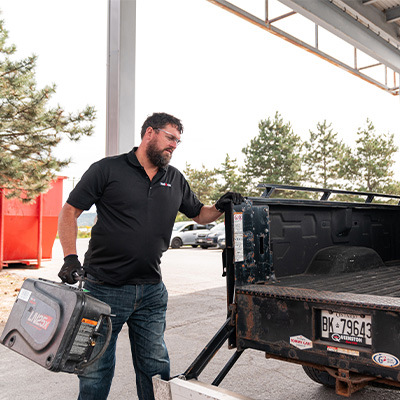 Employee loading welding equipment into the back of a company truck for delivery