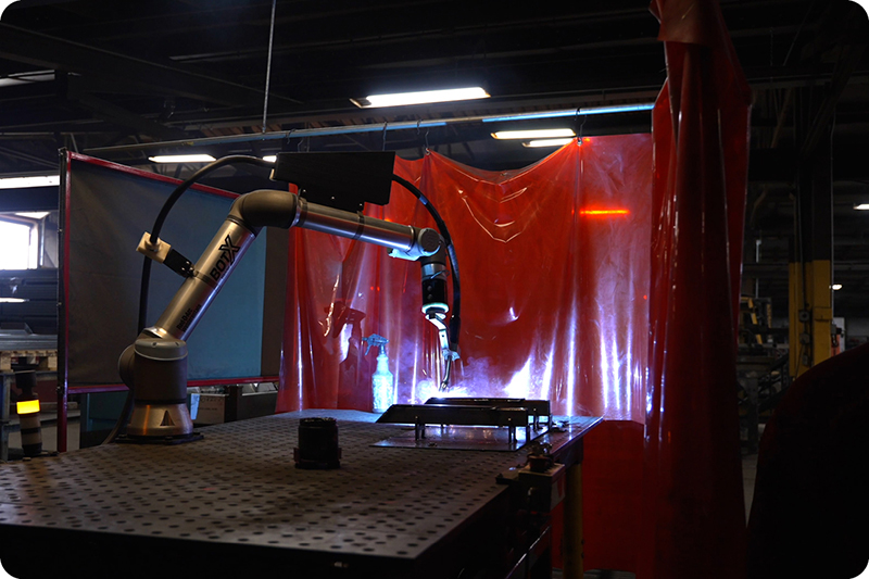 Système de soudage cobot BotX soudant dans un atelier sombre