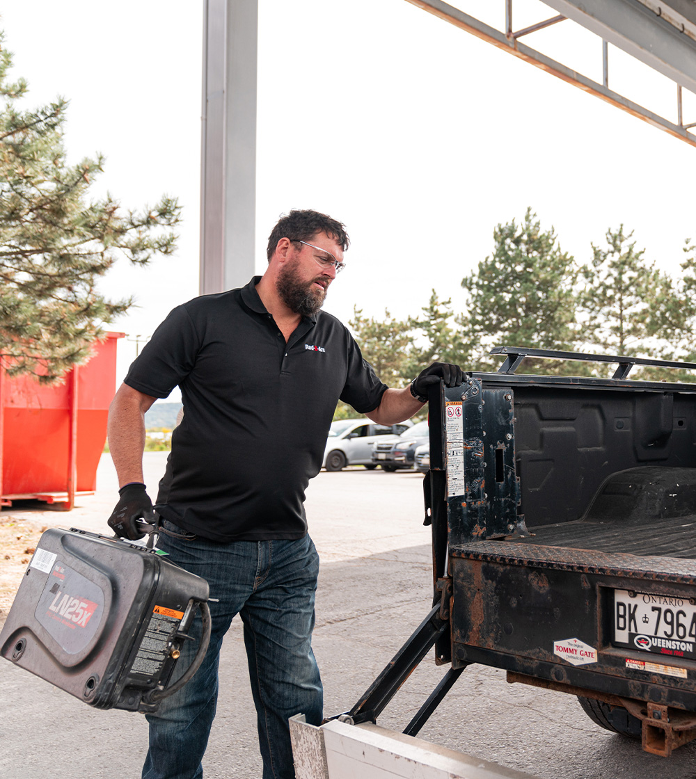 Employee loading welding equipment into the back of a truck preparing for a delivery