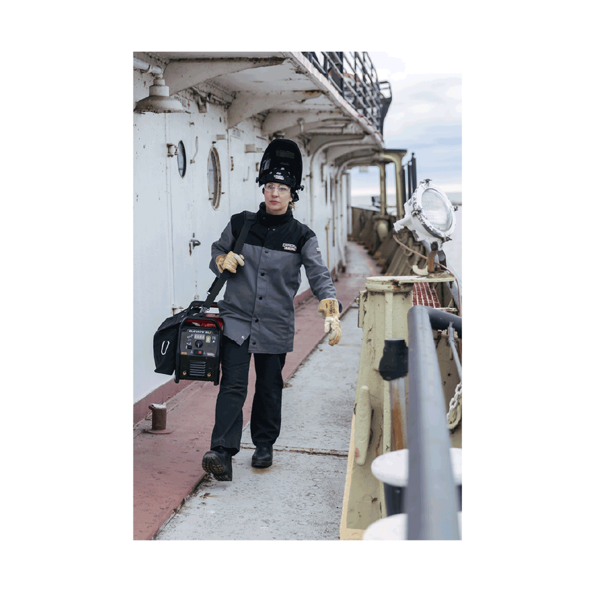 Women welder walking on ship carrying the ELEVATE SLi Battery Welder.