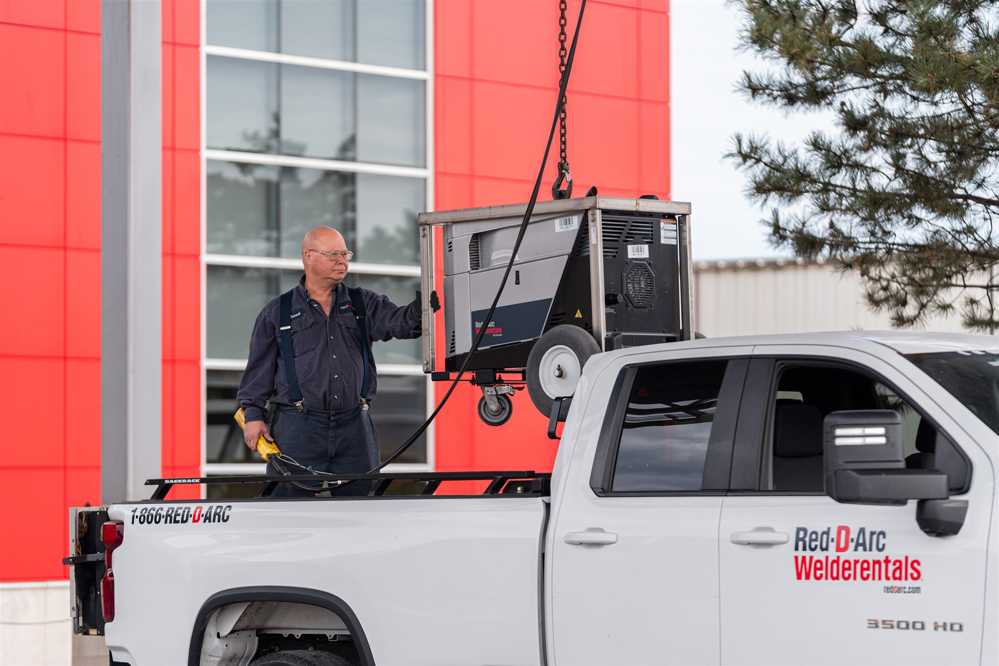 Employee loading welding equipment into the back of a company truck for delivery