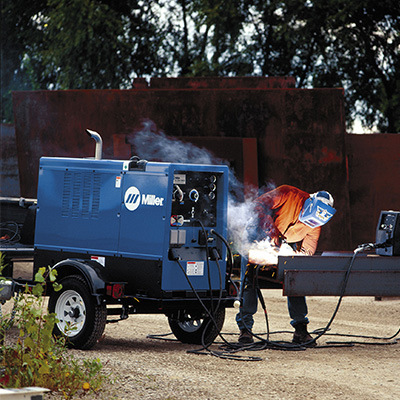 Welder welding steel outside with a Miller branded engine-driven welding machine