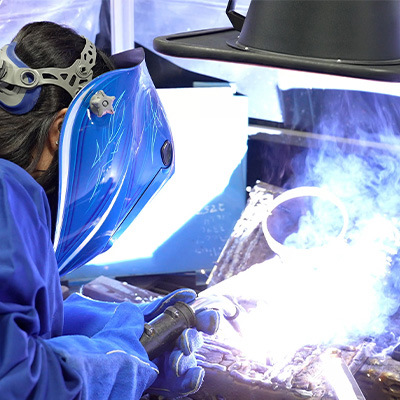 Female welder MIG welding with fume extractor over head