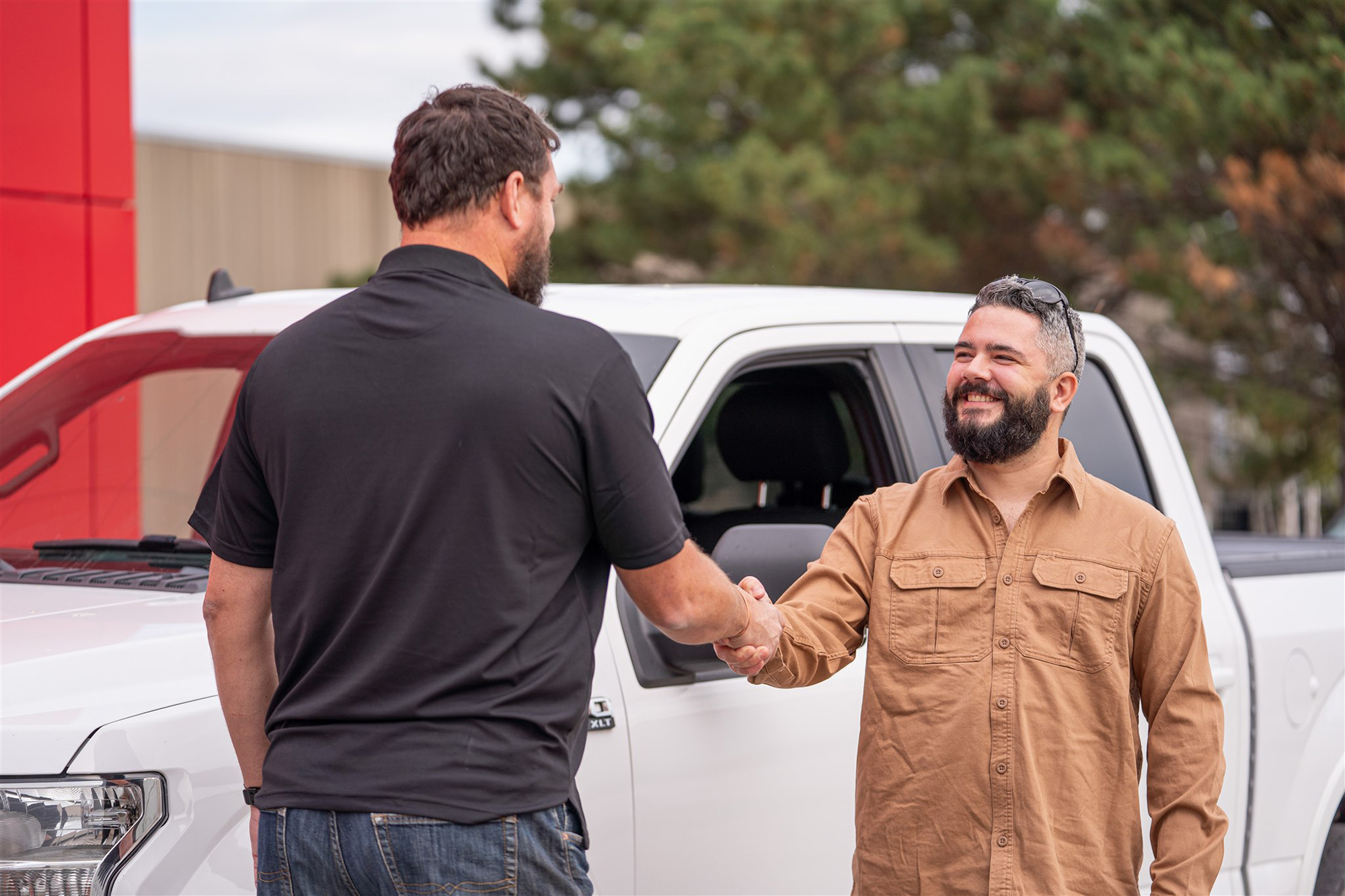 Employee shaking hands with customer on in front of white truck